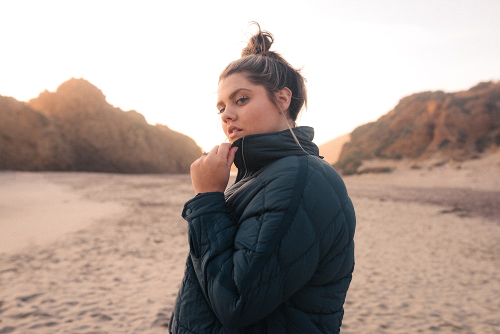 woman in black jacket standing on brown sand during daytime