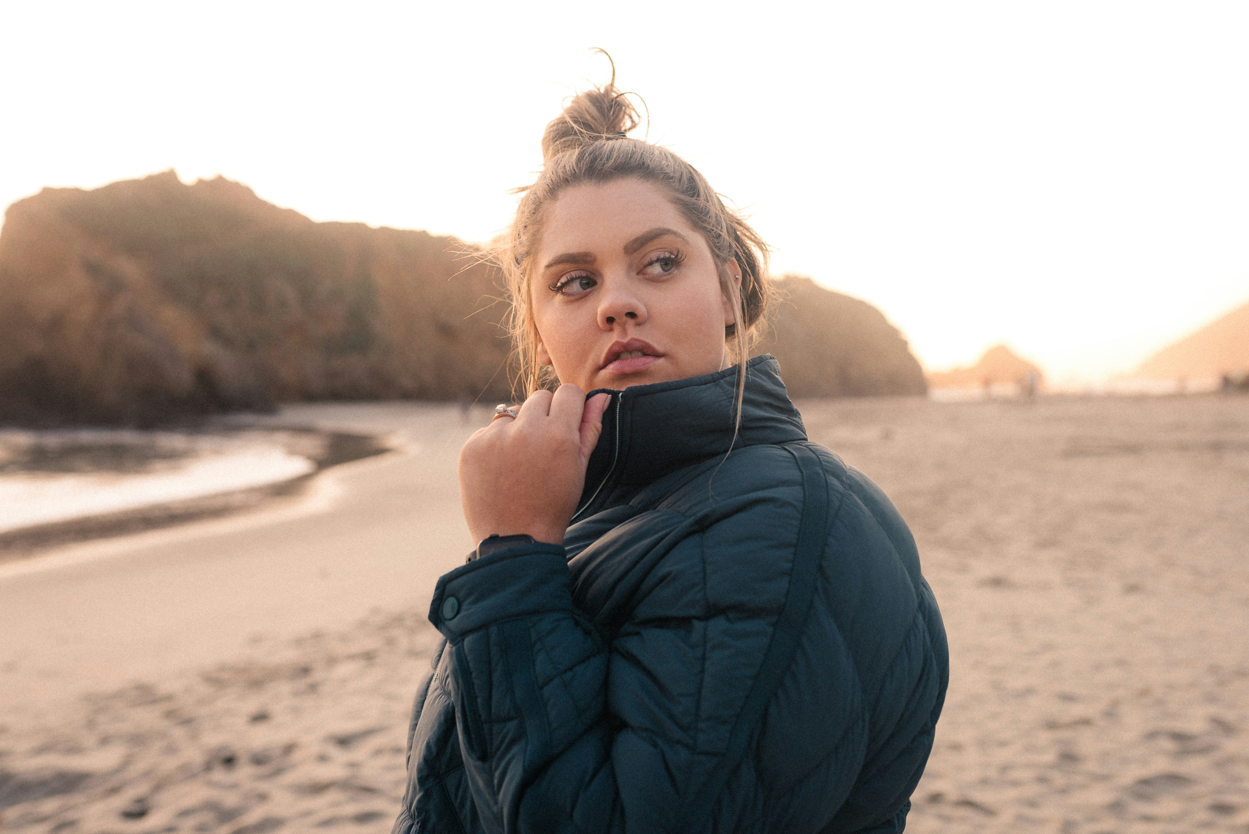 woman in black jacket standing on beach during daytime