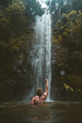 person sitting on rock near waterfalls during daytime