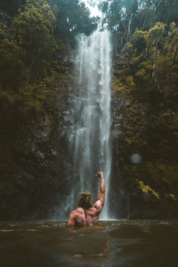 person sitting on rock near waterfalls during daytime
