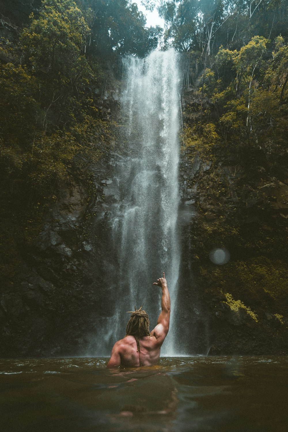 person sitting on rock near waterfalls during daytime