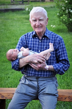 man in blue and white plaid button up shirt carrying baby