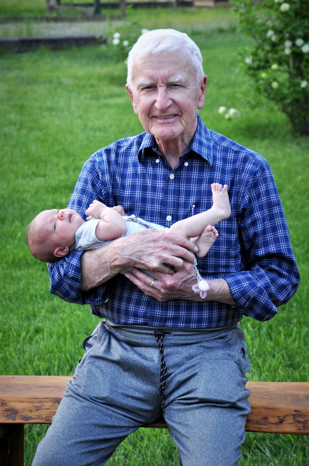 man in blue and white plaid button up shirt carrying baby