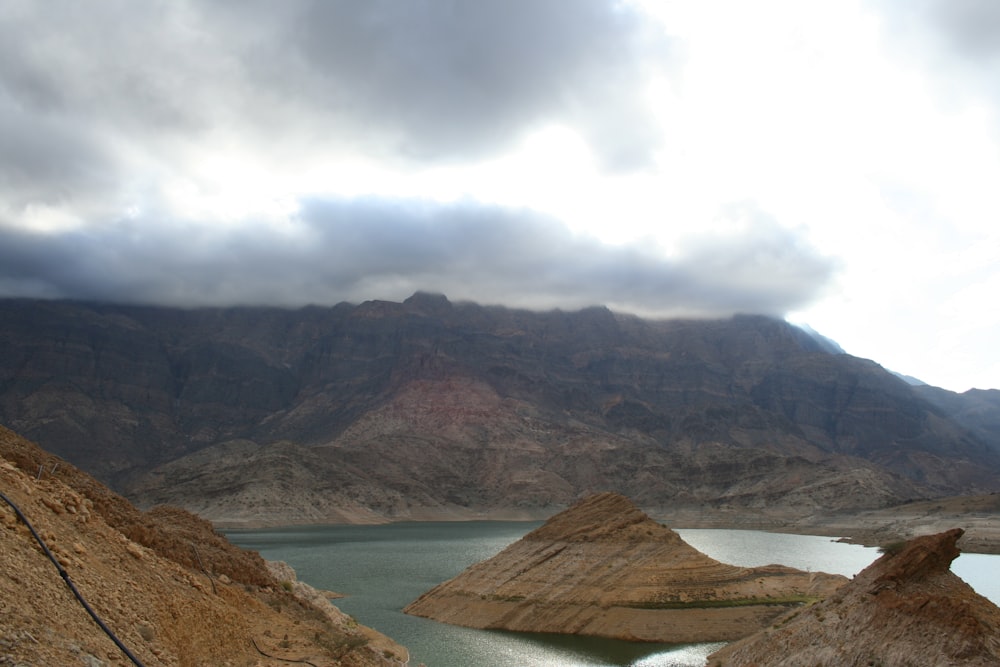 brown mountain near body of water during daytime