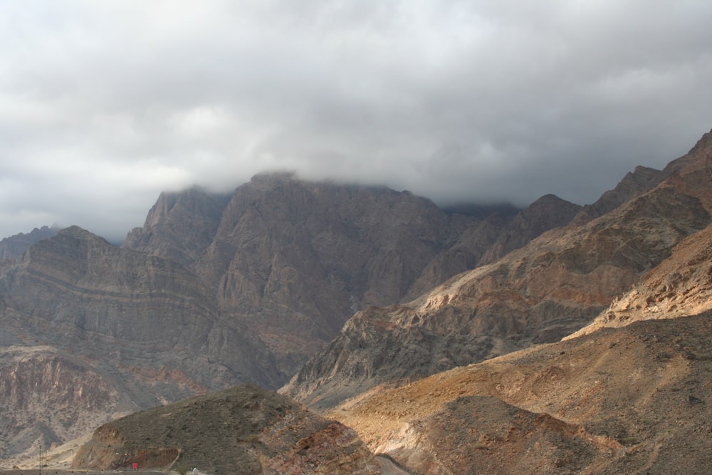 Montaña rocosa marrón y gris bajo cielo nublado blanco durante el día