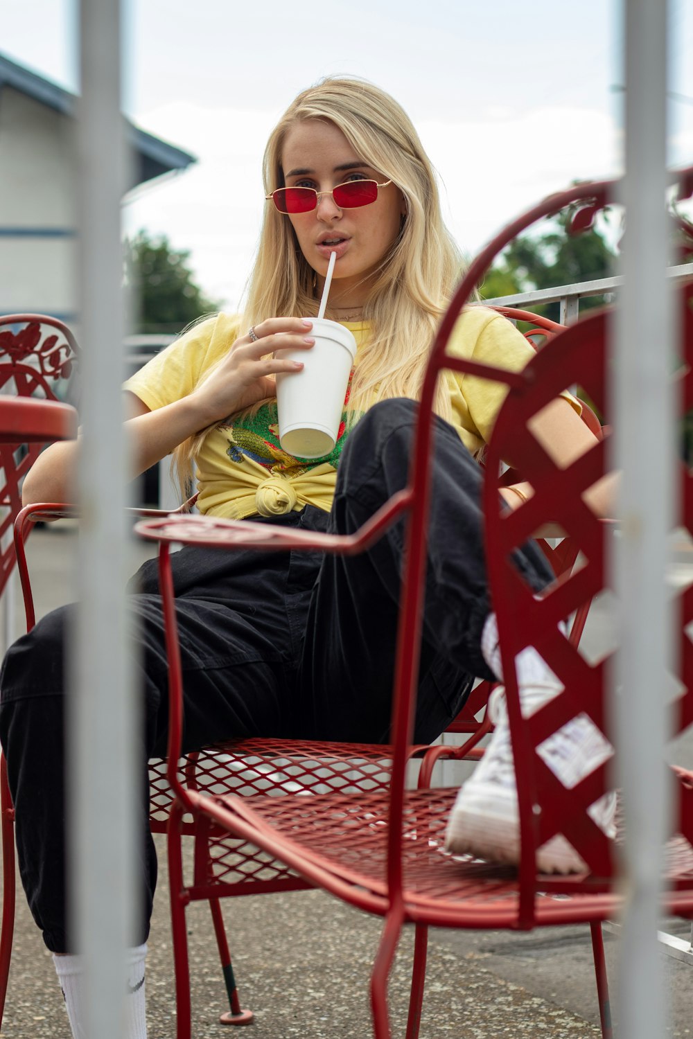 woman in black shirt holding white ceramic mug sitting on red chair