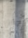 A textured concrete wall with visible signs of wear and a vertical shadow cast across part of its surface. The wall displays a rough texture with small holes and marks from the construction process.