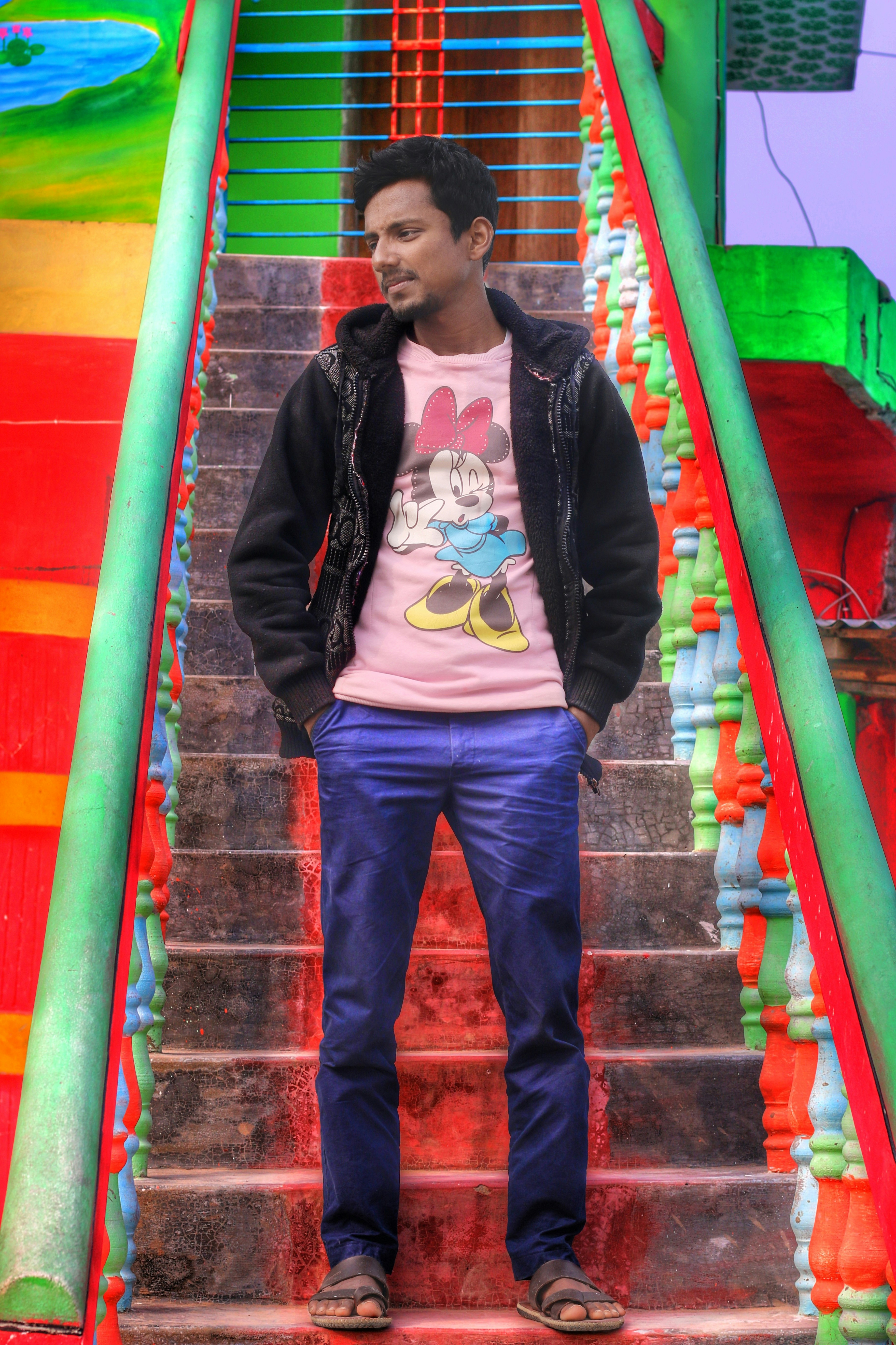 girl in black jacket and blue pants standing on red and yellow staircase