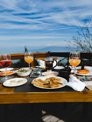 Bright and inviting brunch table with fresh pastries, fruits, and coffee on a wooden deck.