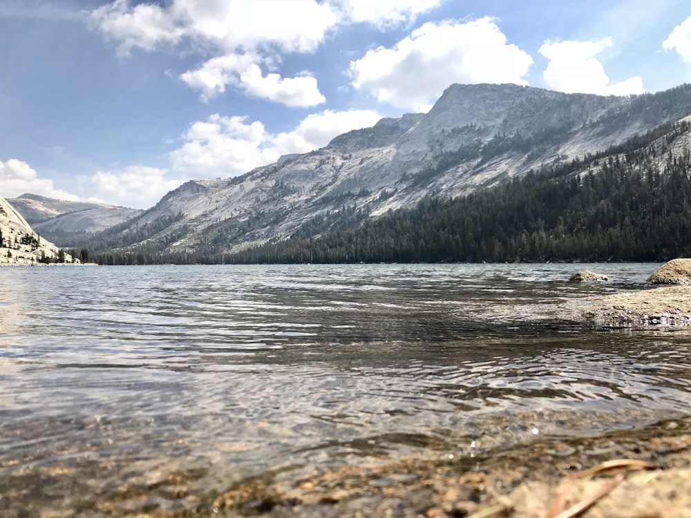 body of water near mountain under blue sky during daytime