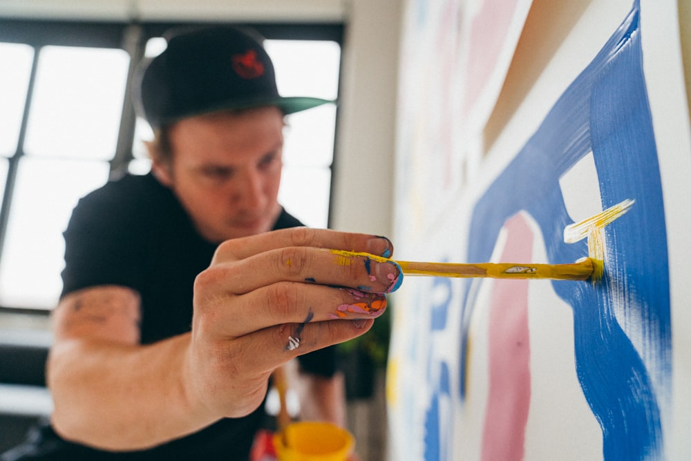 man in black crew neck shirt holding yellow paint brush