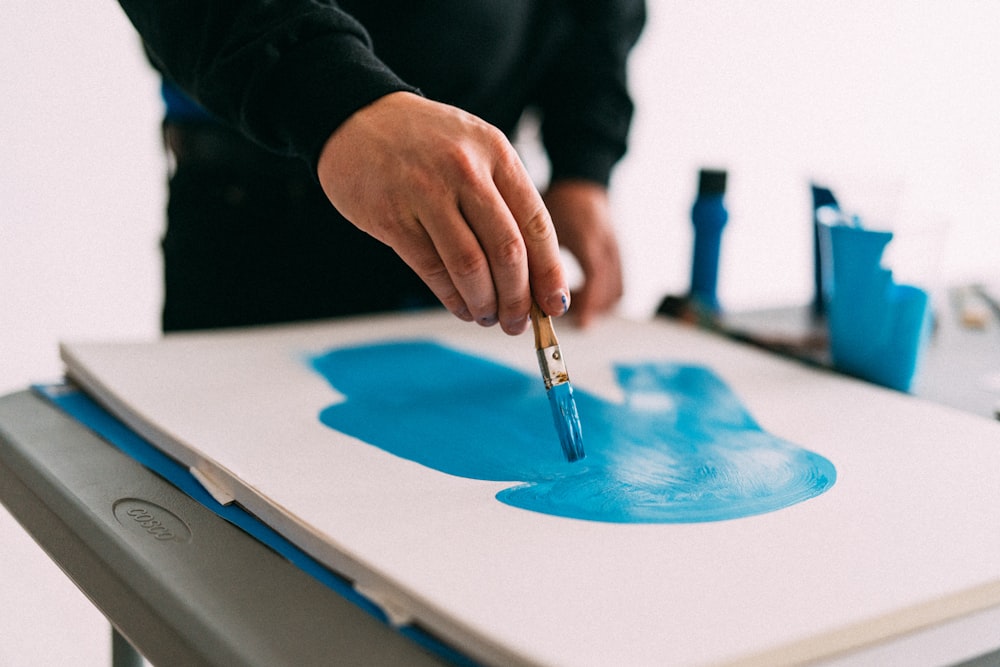 person holding blue paint brush