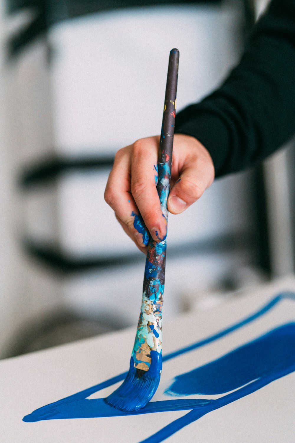 person holding blue and white paint brush