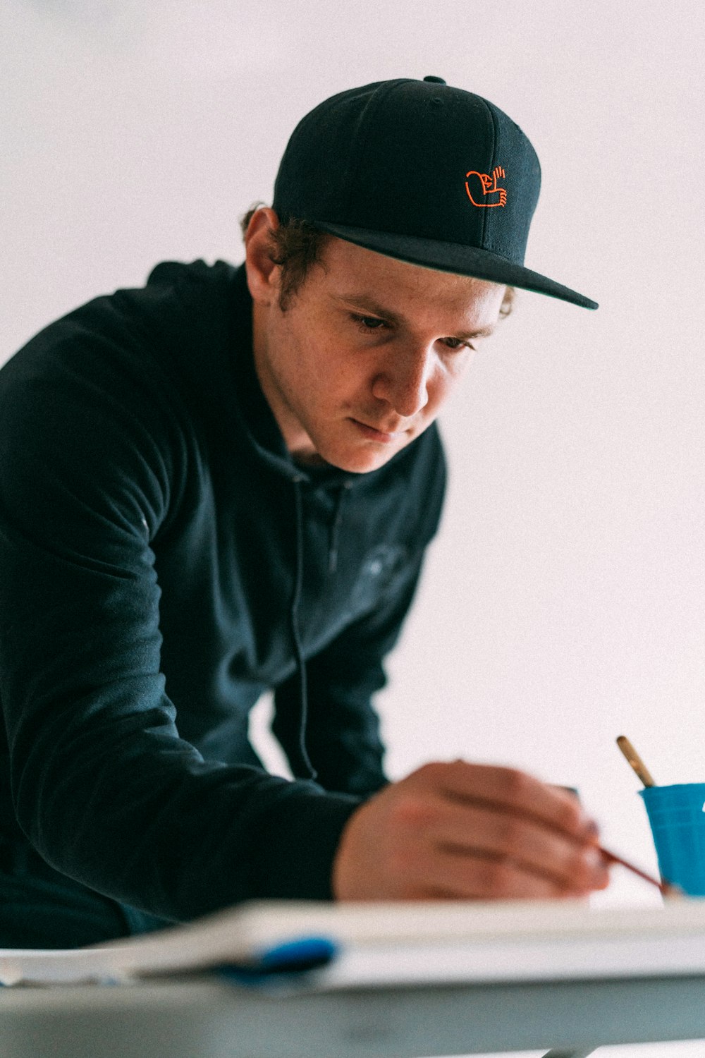 man in black long sleeve shirt and black cap holding pen