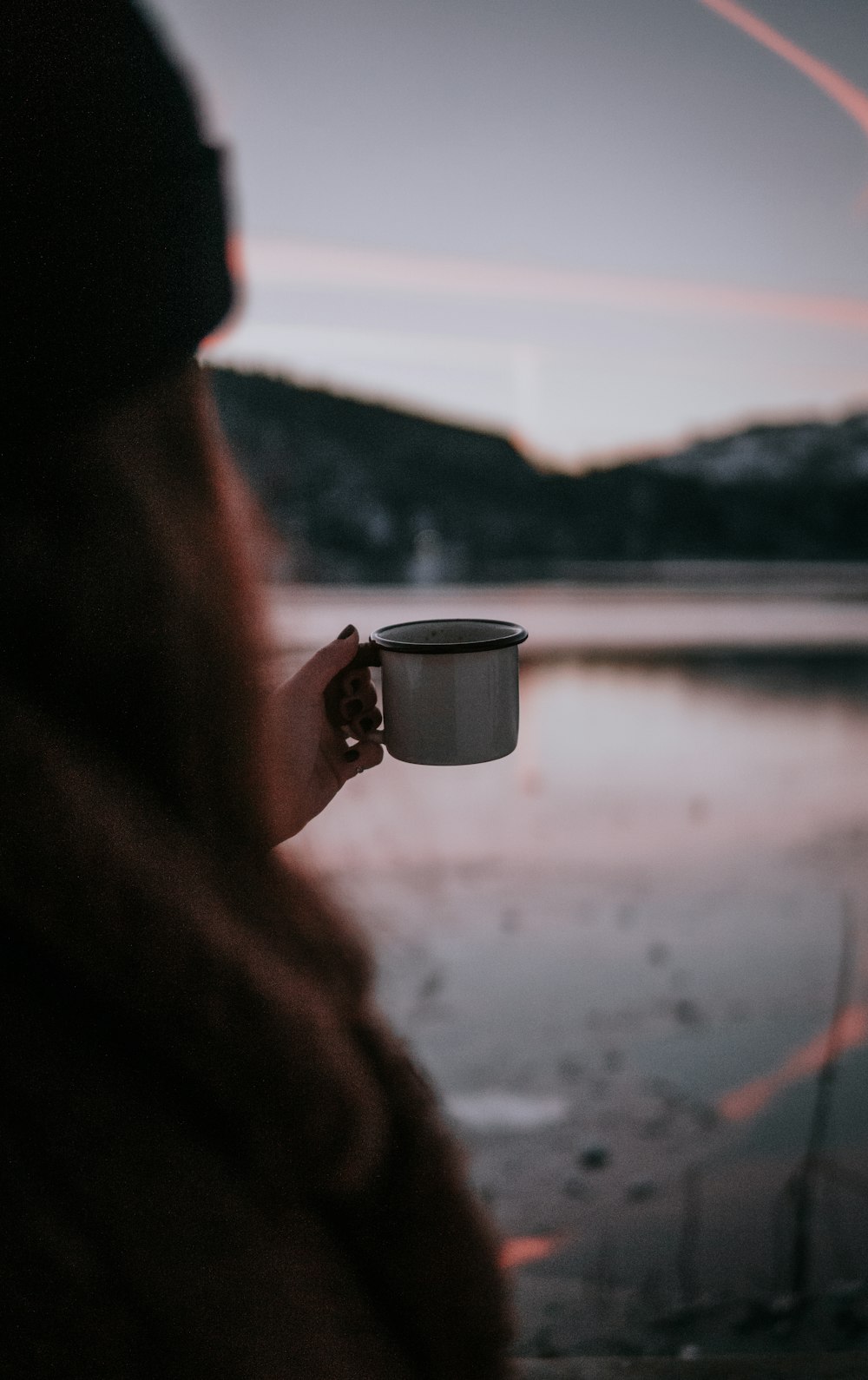 personne tenant une tasse en céramique blanche