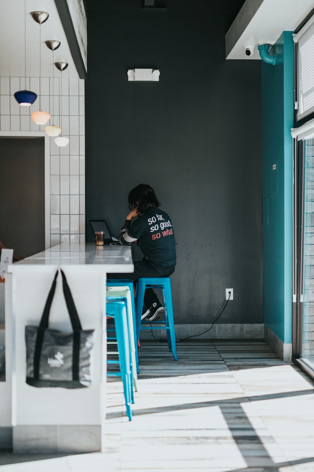 man in black hoodie sitting on blue stool