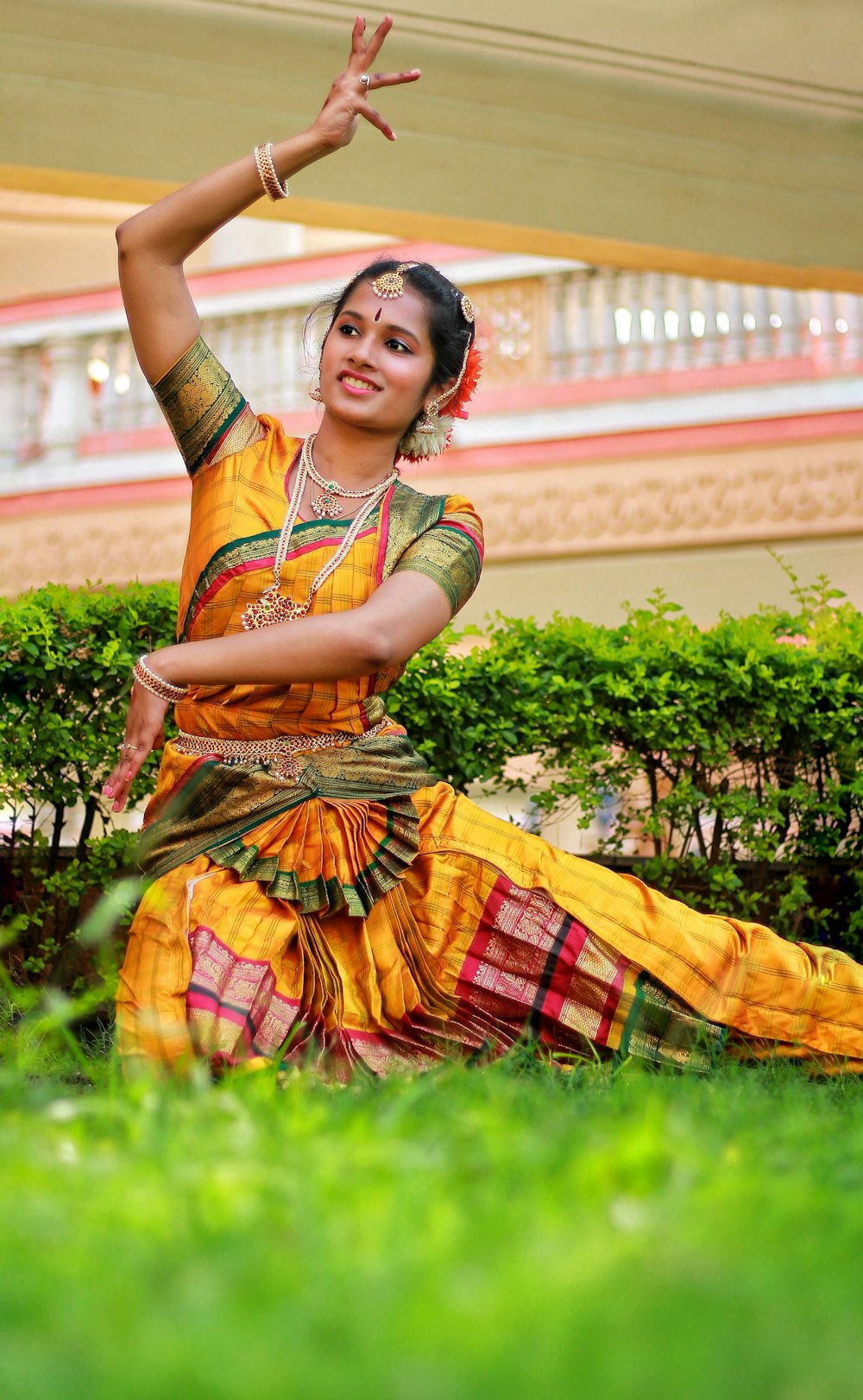 woman in orange and yellow dress standing on green grass field during daytime