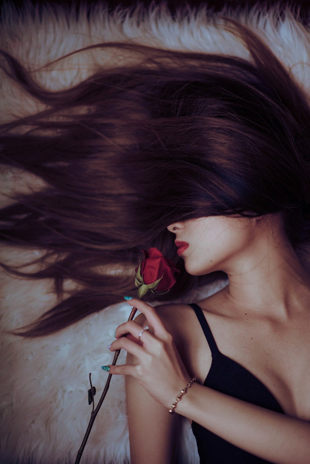 woman in black tank top holding red rose