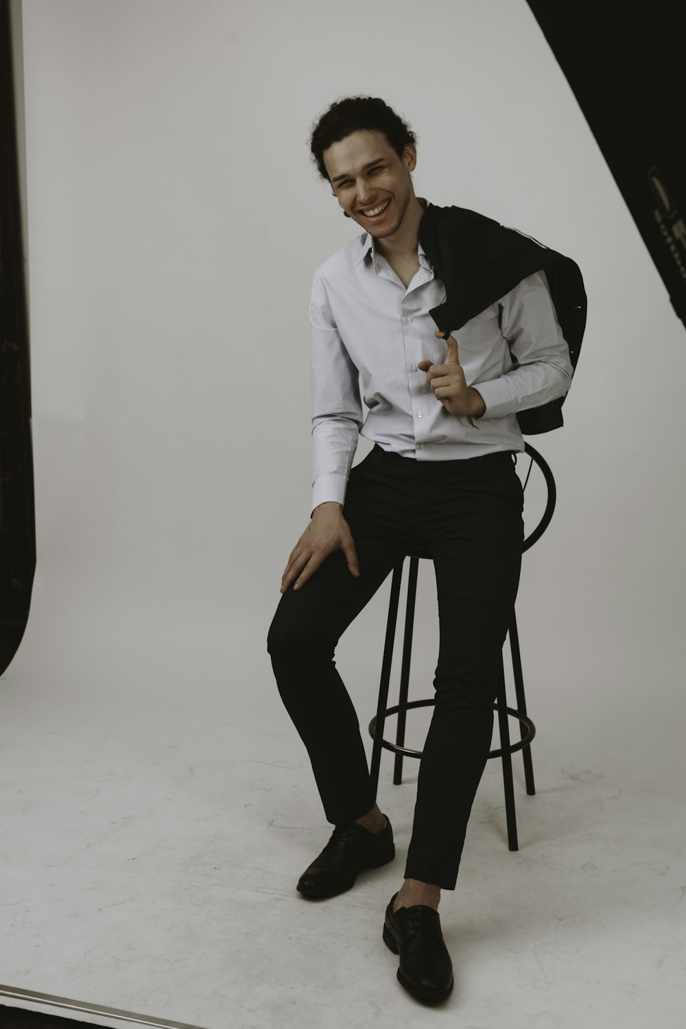 woman in white dress shirt and black pants sitting on black stool