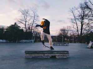 Dynamic shot of a skateboarder wearing hood drip apparel mid-trick in a skate park