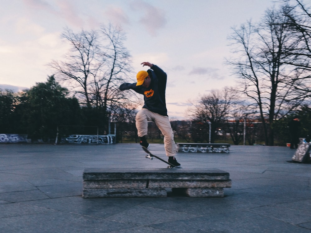 Uomo in giacca nera e pantaloni bianchi che gioca skateboard durante il giorno