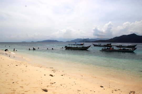 blue and white boat on sea during daytime in Pulau Sirandah Indonesia