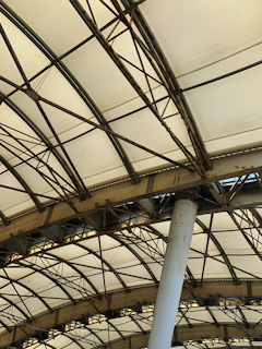 Detail of a welded metal frame supporting a glass canopy on a commercial storefront.