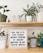 A close-up of colorful potted plants with motivational quote tags displayed on a wooden shelf.