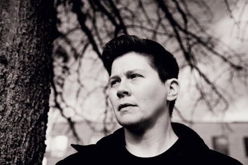 Black and white portrait of a transgender person looking thoughtfully into the distance.