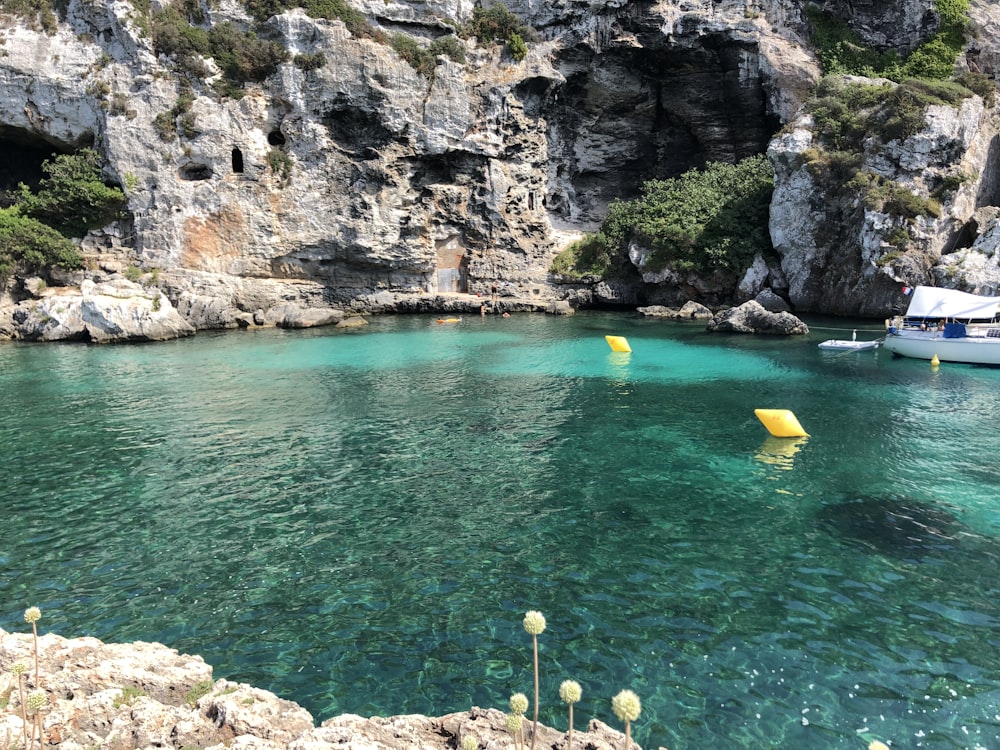 Kayak amarillo y azul en el agua azul del mar cerca de la Montaña Rocosa Gris durante el día