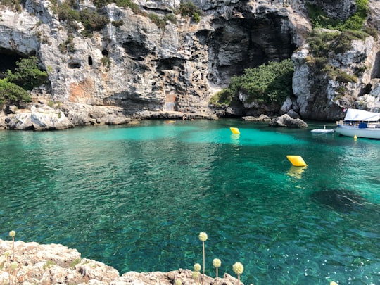 yellow and blue kayak on blue sea water near gray rocky mountain during daytime in Cales Coves Spain