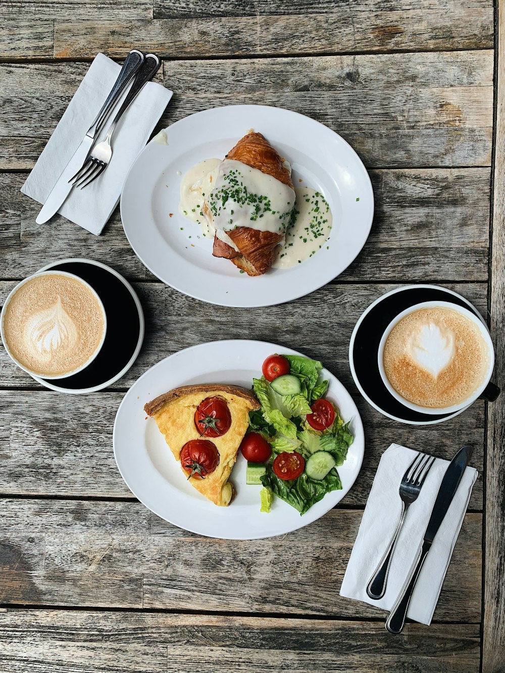 sliced tomato and green leaf vegetable on white ceramic plate beside stainless steel fork and bread