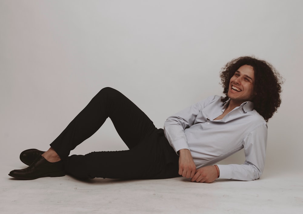 woman in white dress shirt and black pants sitting on white floor