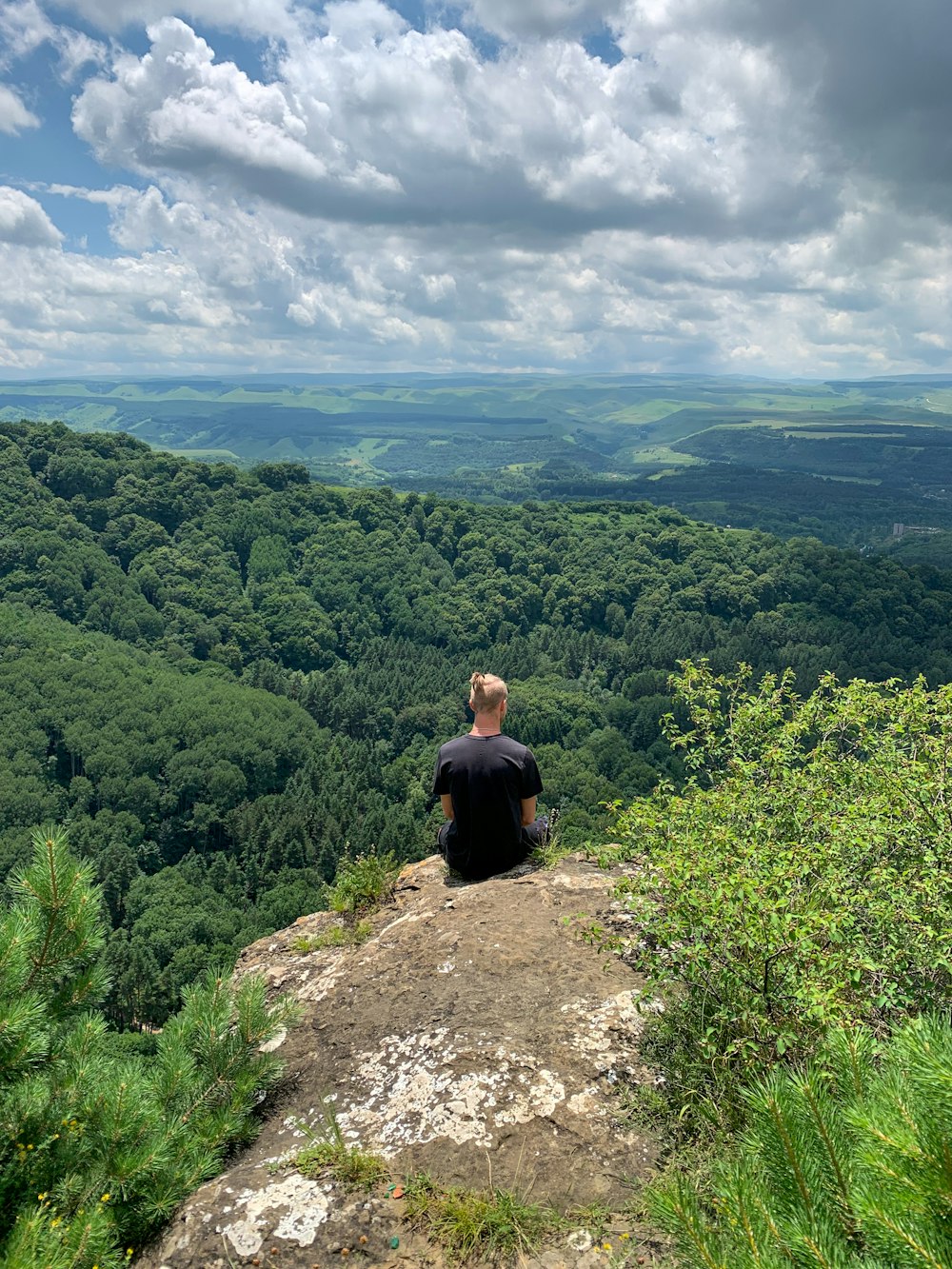 man in black shirt sitting on rock during daytime