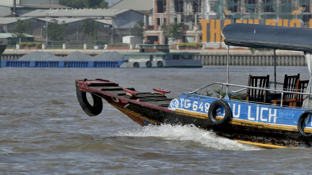 barco vermelho e preto na água durante o dia