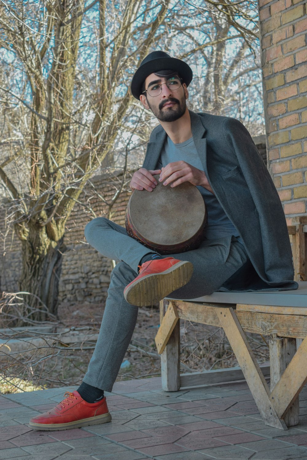 man in black suit jacket sitting on brown wooden chair