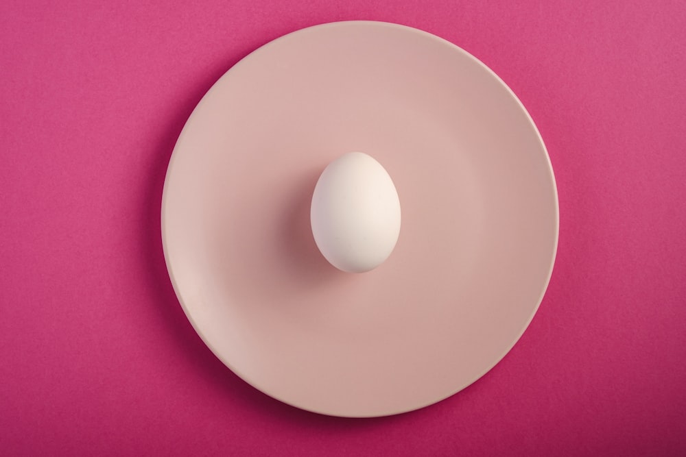 weißer runder Teller auf rosa Textil
