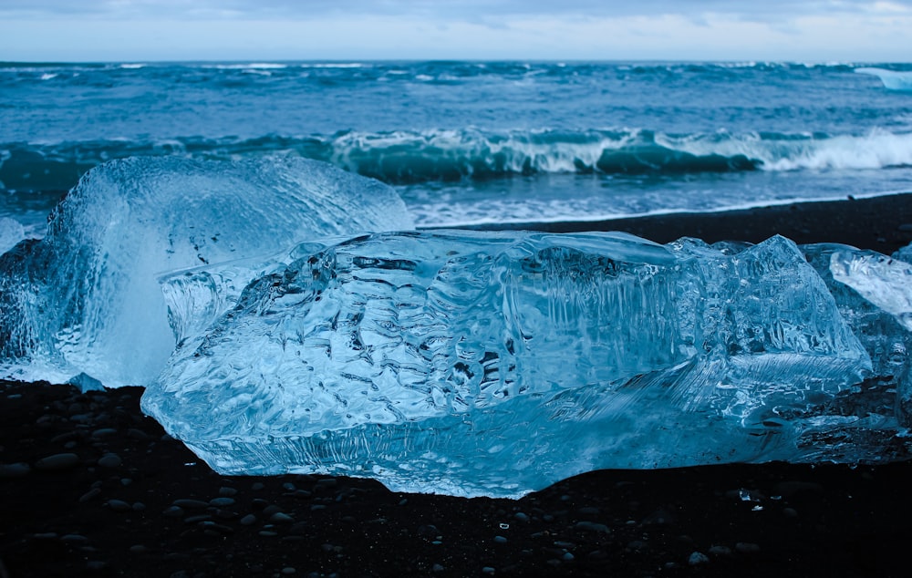 white ice on black sand near sea during daytime