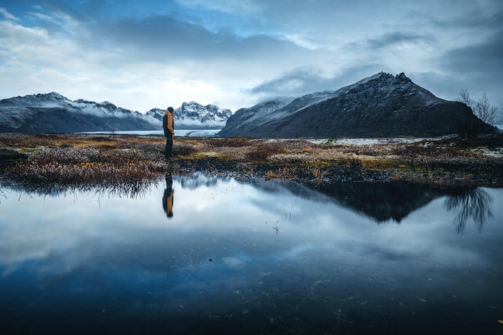 lake near mountain under cloudy sky during daytime