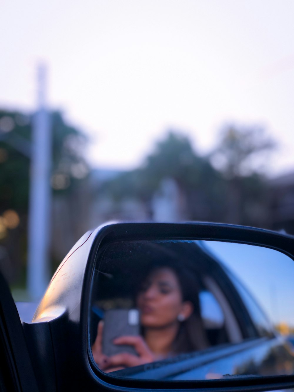 woman in black framed car side mirror