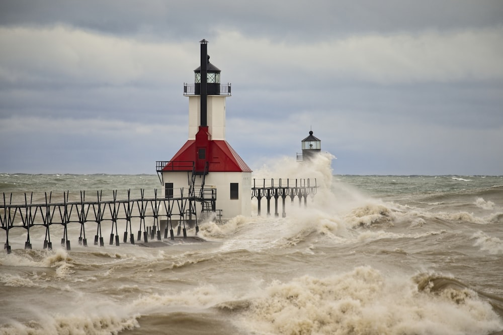 white and red lighthouse on sea shore during daytime