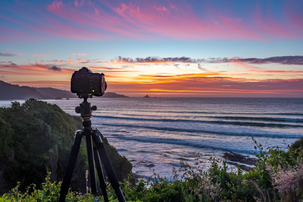 black dslr camera on tripod on seashore during sunset