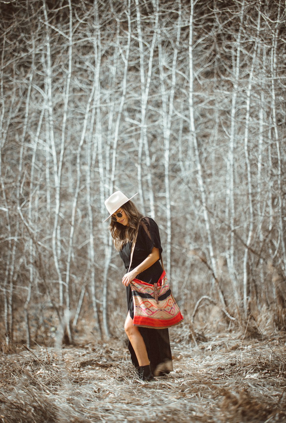 woman in red dress wearing white hat standing in the woods during daytime