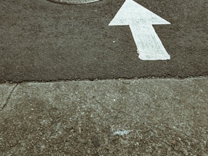 white arrow sign on gray concrete floor