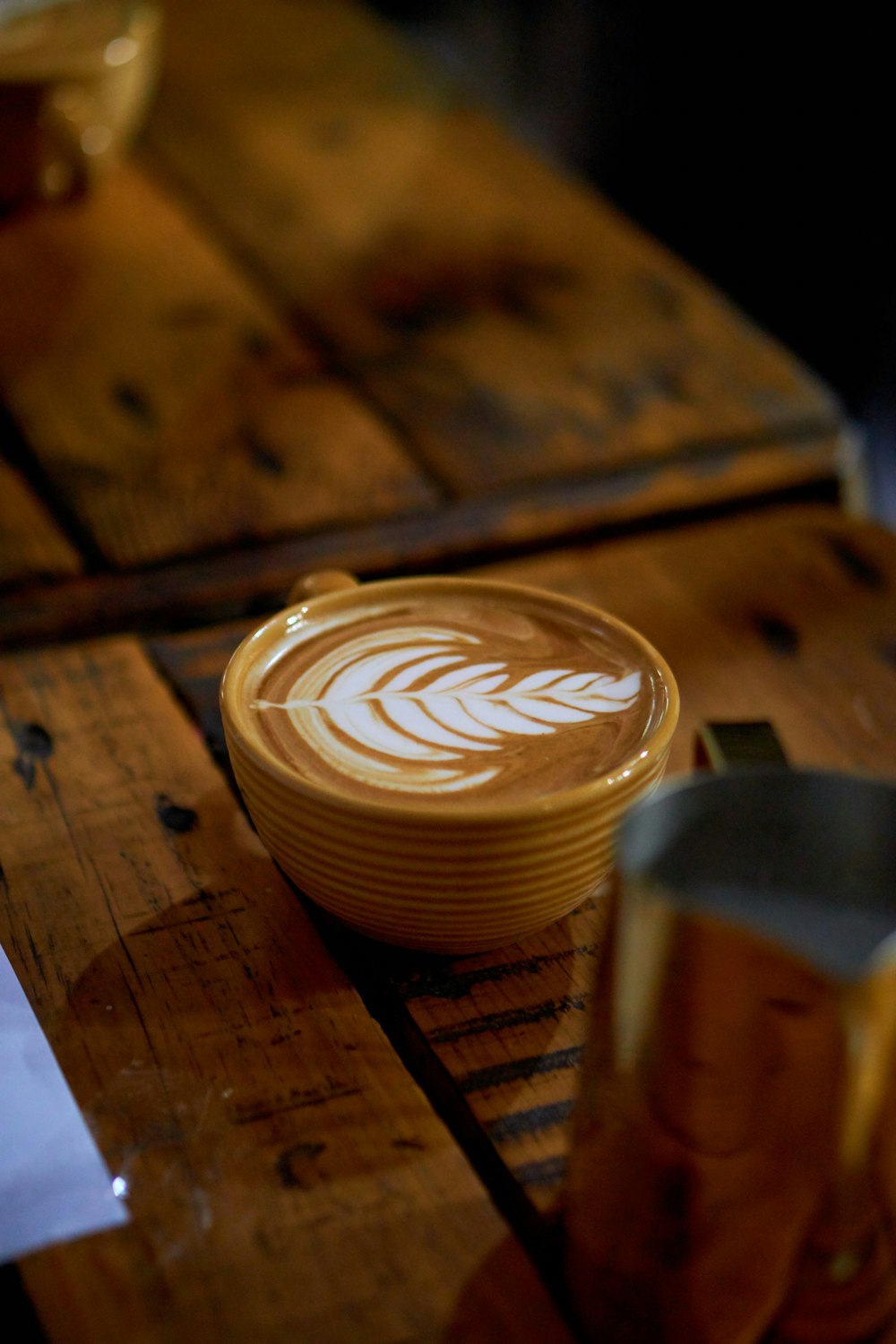 茶色の木製のテーブルに茶色のセラミックマグカップのカプチーノ