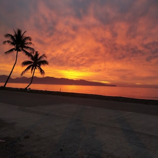 A stunning sunset over the Red Sea with calm waters and distant mountains.
