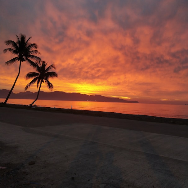 A stunning sunset over the Red Sea with calm waters and distant mountains.