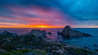 rocky shore under orange and blue sky
