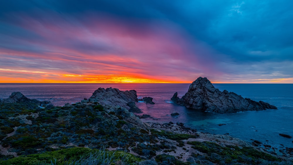 rocky shore under orange and blue sky