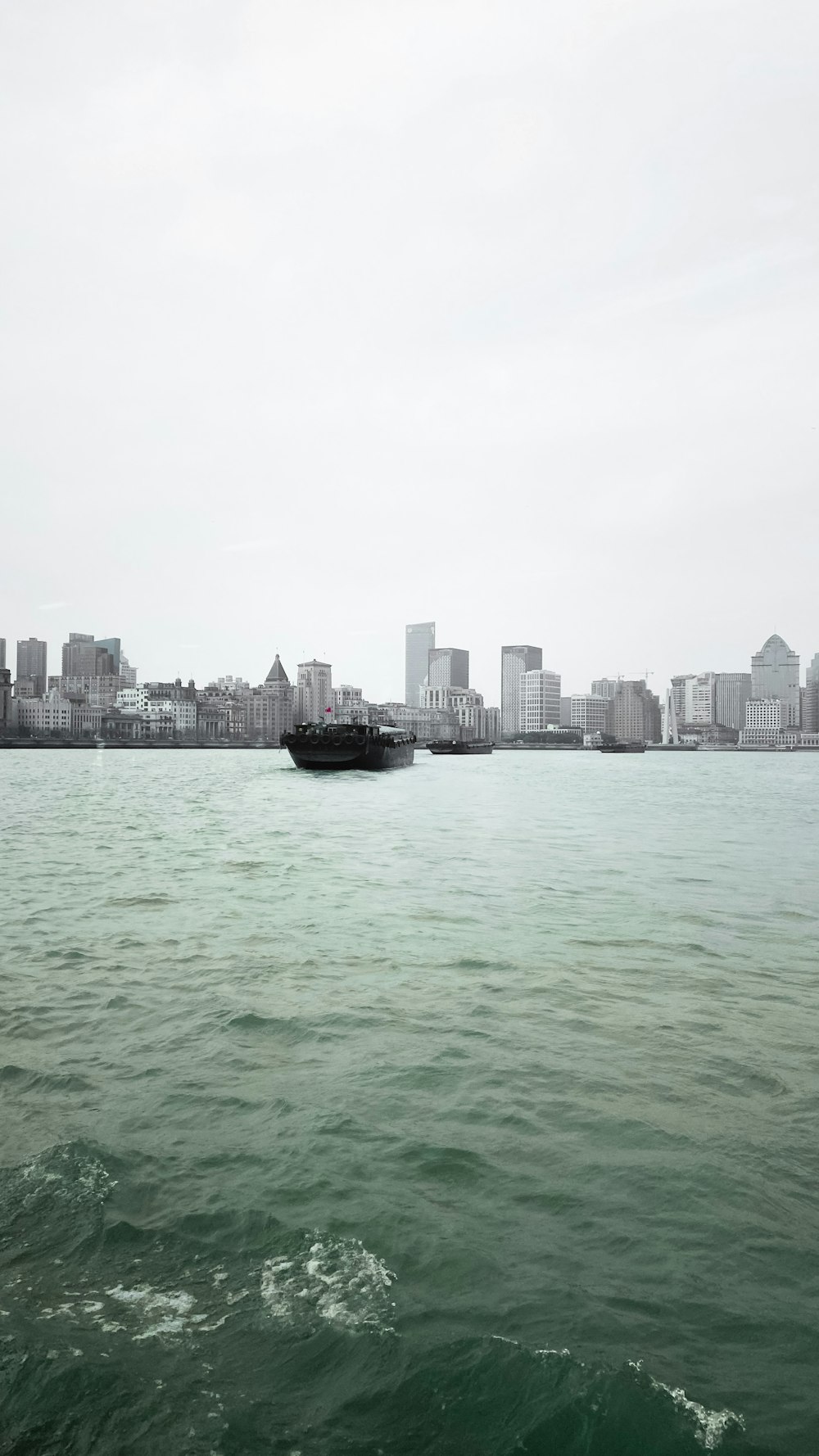 black boat on sea near city buildings during daytime